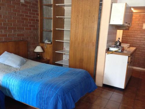 a bedroom with a bed with a blue blanket at Aparthotel San Francisco in Santiago