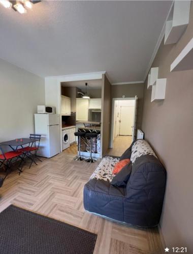 un salon avec un canapé bleu et une cuisine dans l'établissement Charmant studio, à Villeneuve-Loubet