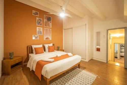 une chambre avec un grand lit aux murs orange dans l'établissement OIQIA • Solis • Azur, à Narbonne