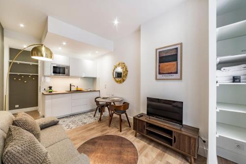 un salon avec un canapé et une télévision et une cuisine dans l'établissement L'absinthe AIL, à Villeurbanne