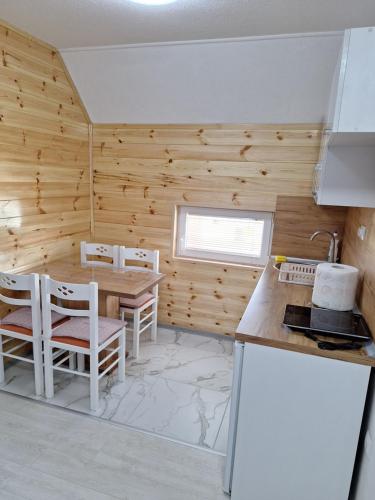 a kitchen with wooden walls and a table and chairs at Apartmani Srećko in Žabljak