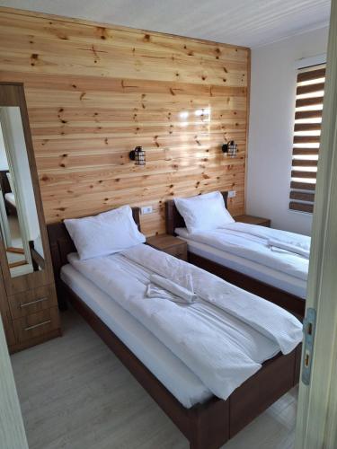 two beds in a room with a wooden wall at Apartmani Srećko in Žabljak