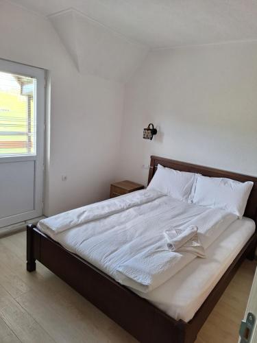 a bedroom with a bed with white sheets and a window at Apartmani Srećko in Žabljak