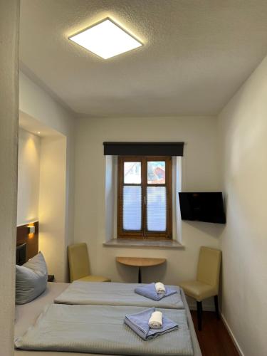 a room with two beds and a table and a window at Gasthof Löwen in Pfronten
