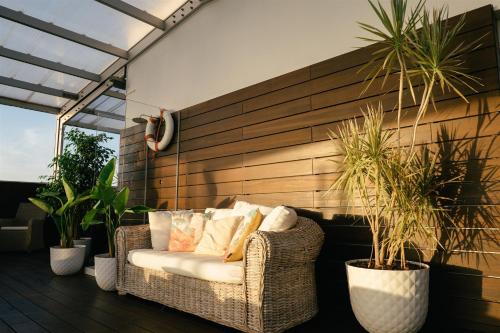 a wicker chair sitting on a patio with plants at Macarico Beach Hotel in Praia de Mira