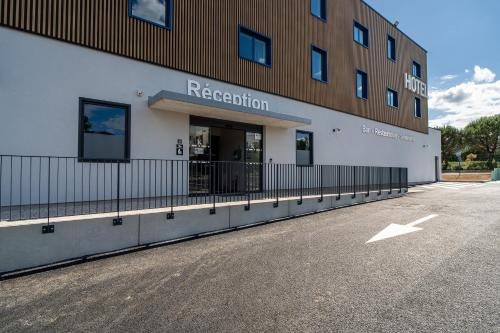 a building with a parking lot in front of it at Kyriad Limoges - Ester in Limoges