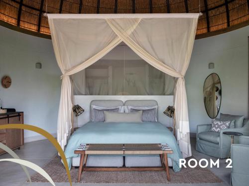 a bedroom with a bed with a canopy and a chair at Fifty-Five Mjejane in Hectorspruit