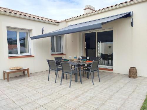 d'une terrasse avec une table, des chaises et un auvent bleu. dans l'établissement Maison de vacances, cosy, bohème chic, avec jardin!, à Bois-de-Cené