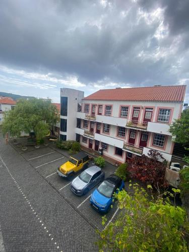 two cars parked in a parking lot in front of a building at Apartamentos Turisticos Verdemar in Horta