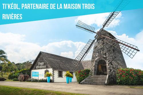 a windmill in front of a building at Résidence Ti'Kéol - Appartements avec terrasse 2 à 4 personnes, piscine in Sainte-Anne