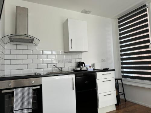 ボルトンにあるStudio in bolton town, Short stay studio 2の白いキャビネットと黒い冷蔵庫のあるキッチン