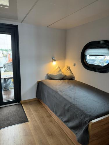 MaasbommelHausboot KOMET Luxus und Natur pur max 5 Pers的一间有窗户的小房间里的一张床