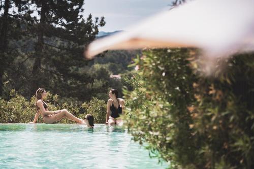 three women sitting in the water in a pool at Les Lodges Sainte-Victoire Hotel & Spa in Aix-en-Provence
