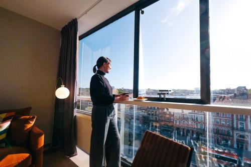 un homme debout devant une grande fenêtre dans l'établissement OIQIA • New Yorker, à Toulouse