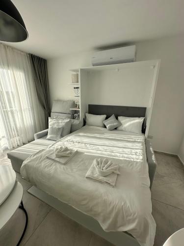 ein großes weißes Bett mit zwei Handtüchern darauf in der Unterkunft Студия в комплексе Thalassa с видом на горы in Elea