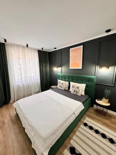 a bedroom with a large bed with a green headboard at Caris Home in Hunedoara