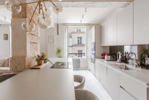 une cuisine avec des placards blancs et un comptoir blanc dans l'établissement 196 Suite Dan - Superbe Appartement à Paris, à Paris