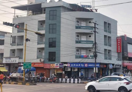 a white car driving down a street in front of a building at Hotel Galaxy in Indore