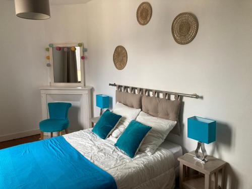une chambre avec un lit avec des oreillers bleus et un miroir dans l'établissement Maison avec grand jardin et terrasse dans quartier de la Bénédictine, à Fécamp