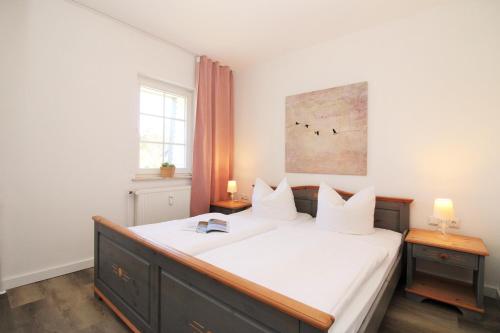 a bedroom with a bed with white sheets and two tables at Ostseeresidenz Appartements Wischuer Fewo 23 in Wischuer
