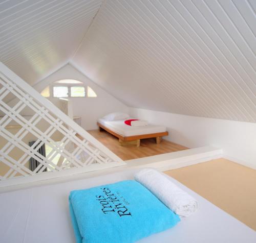 a white attic room with a bed and a bench at Résidence Ti'Kéol - Appartements avec terrasse 2 à 4 personnes, piscine in Sainte-Anne