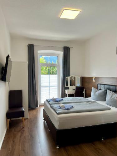 a bedroom with a bed and a chair and a window at Gasthof Löwen in Pfronten