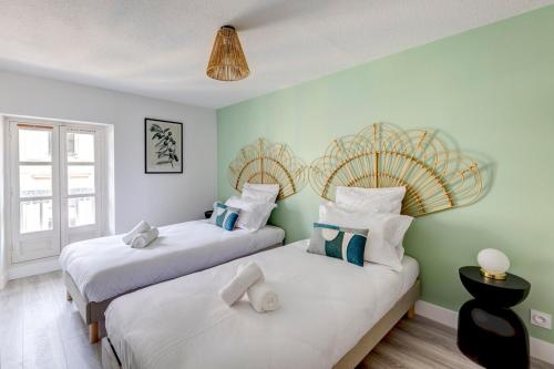 deux lits dans une chambre aux murs verts dans l'établissement OIQIA • Hesperis, à Sarlat-la-Canéda