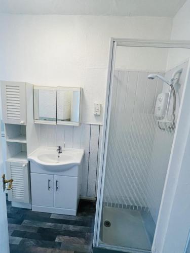 a white bathroom with a sink and a shower at Henson hotel in Blackpool