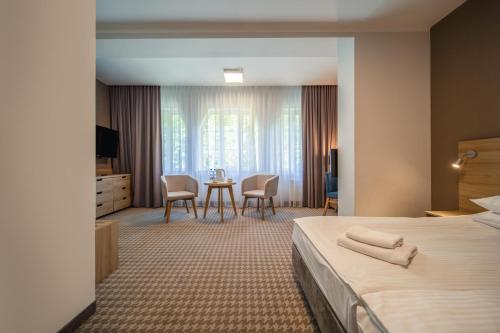 a hotel room with a bed and a table and chairs at Medical Sensus in Polanica-Zdrój
