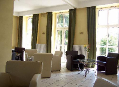 a waiting room with chairs and tables and windows at Hotel am Ceresplatz in Manderscheid