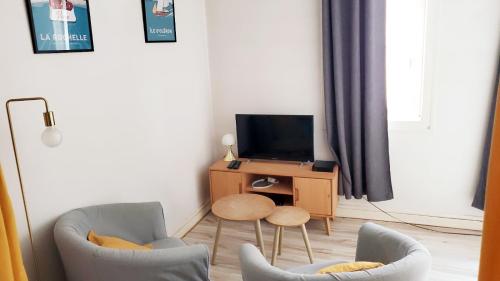 un salon avec deux chaises et une télévision dans l'établissement Cosy Studio près du Vieux Port de La Rochelle, à La Rochelle
