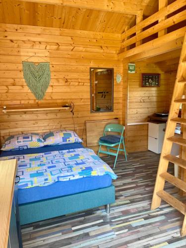 a bedroom with a bed and a chair in a log cabin at Pokoje i domki letniskowe BROS in Dziwnów