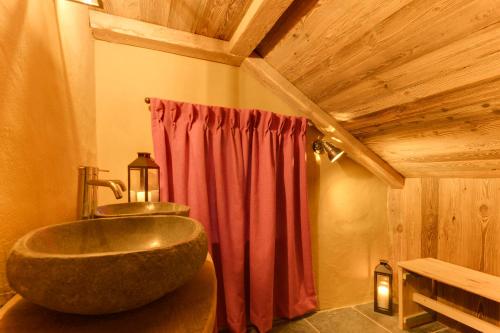 a bathroom with a large sink and a red curtain at Les Cabanes de Rensiwez in Mabompré
