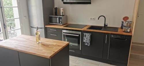 cocina con electrodomésticos negros y encimera de madera en Au cœur des Caladons, en Lunel