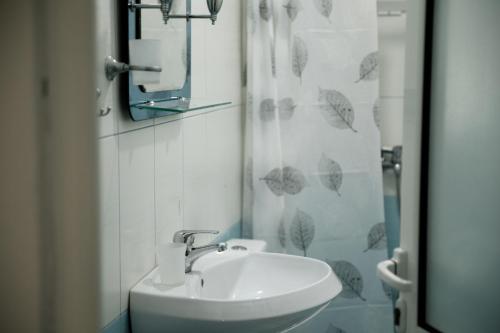 un bagno con un lavandino e una tenda da doccia con ombrelli di City Side a Gjirokastër