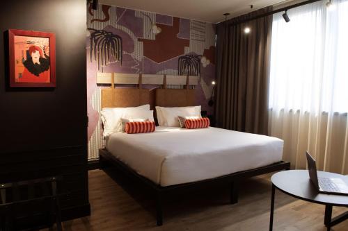 a bedroom with a bed and a laptop on a table at Mercure Roma Cinecittà in Rome