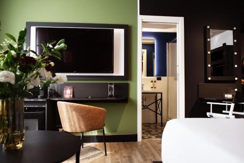 a room with a tv and a table with a vase of flowers at Mercure Roma Cinecittà in Rome