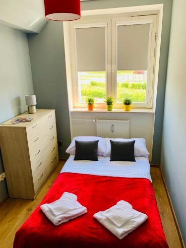 a bedroom with a bed with a red blanket and a window at Apartament Rondo AC Progres in Toruń