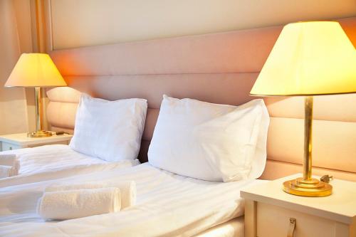 a bed with white pillows and two lamps on tables at Villa Lessing in Polanica-Zdrój