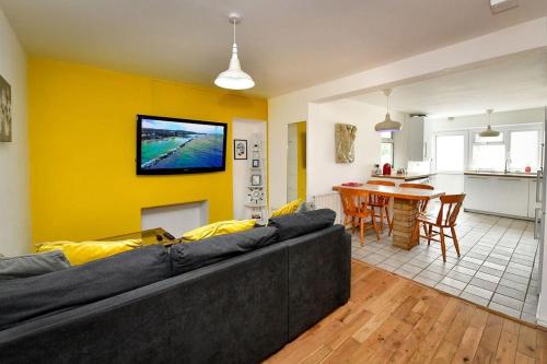 a living room with a couch and a tv on a yellow wall at Host & Stay - Oxford Street House in Swansea