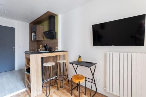 un salon avec un bar avec tabourets et une télévision dans l'établissement L'Irazu ~ Centre-ville ~ Climatisation, à Clermont-Ferrand