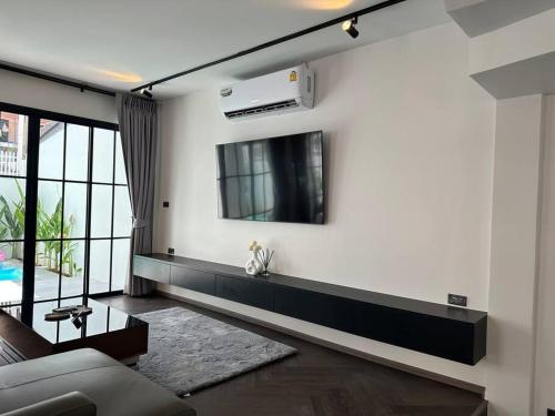a living room with a couch and a tv on a wall at House 148 Patong Pool Villa 4BR Near Beach in Patong Beach