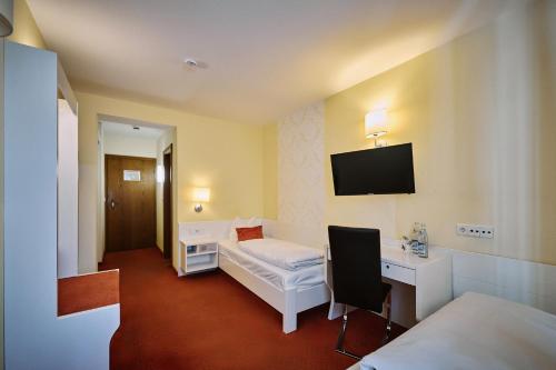 a room with a bed and a desk and a tv at Herdegen Rooms - Self Check-in in Passau