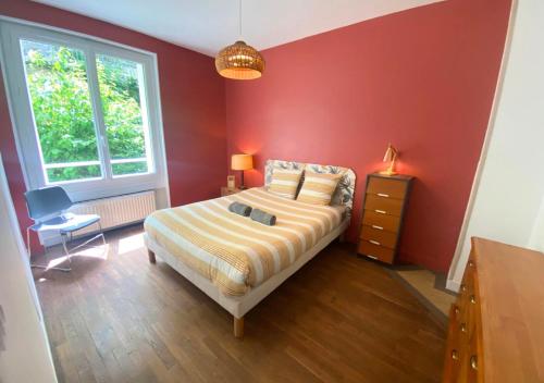 une chambre avec un lit et un mur rouge dans l'établissement Le Grand Cerf - Poitiers - Gare, à Poitiers