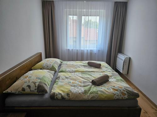 a bedroom with a bed with two pillows and a window at Apartmány Skalica in Skalica