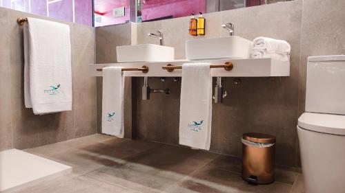 a bathroom with two sinks and towels and a toilet at Hotel Ritual Torremolinos- Adults Only in Torremolinos