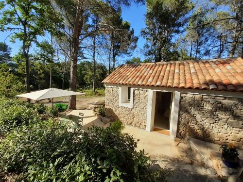 une maison en pierre avec une terrasse et un parasol dans l'établissement La Bergerie, à Lorgues