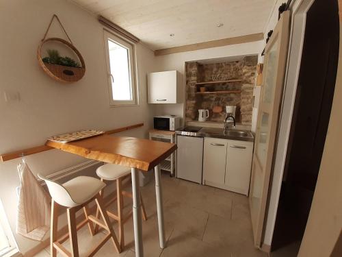 una pequeña cocina con mesa de madera y sillas en La Bergerie, en Lorgues