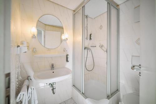 a white bathroom with a sink and a shower at Herdegen Rooms - Self Check-in in Passau