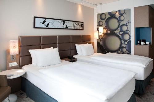 two beds in a hotel room with white sheets at Holiday Inn Berlin City East Side by IHG in Berlin